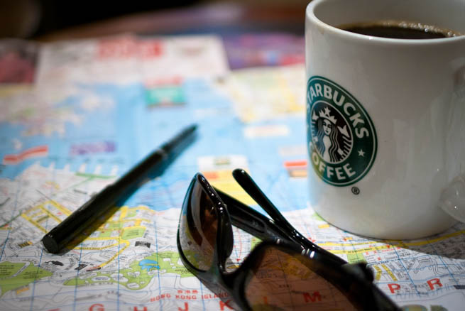 A traveler plans his trip using a map, a pen, and lots of coffee.